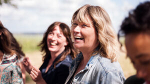 Photo of small group of women smiling as they discuss the importance of nonprofit leadership development evaluation for measuring community impact
