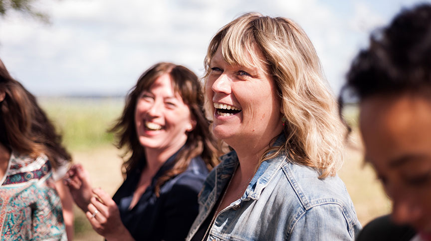 Photo of small group of women smiling as they discuss the importance of nonprofit leadership development evaluation for measuring community impact