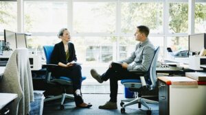 Older woman executive coaching a younger first-line manager on the essential frontline manager skills needed to succeed