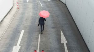 Person walking in the rain; metaphor demonstrating the importance of investing in development in downturns or protecting leadership development budgets during economic uncertainty or recessions