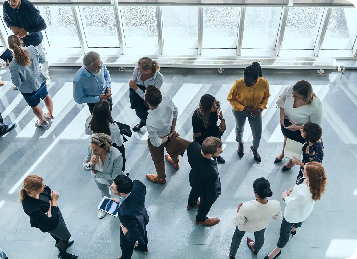 Photo of several professionals, gathered in small groups, discussing leadership in disruption