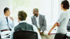 Laughing coworkers discussing project at workstation in office
